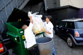 Chef Wilson Mendez, right, and dishwasher Max Rodas throw bags of trash into a single landfill dumpster in the back of Luka's Taproom in Oakland, CA Friday, July 24 2015.  
Because of a significant rate increase for collection in Oakland, Luka's Taproom has decided to stop composting their food waste and instead put all their trash into a landfill dumpster. Photo: Michael Short / Special To The Chronicle / ONLINE_YES